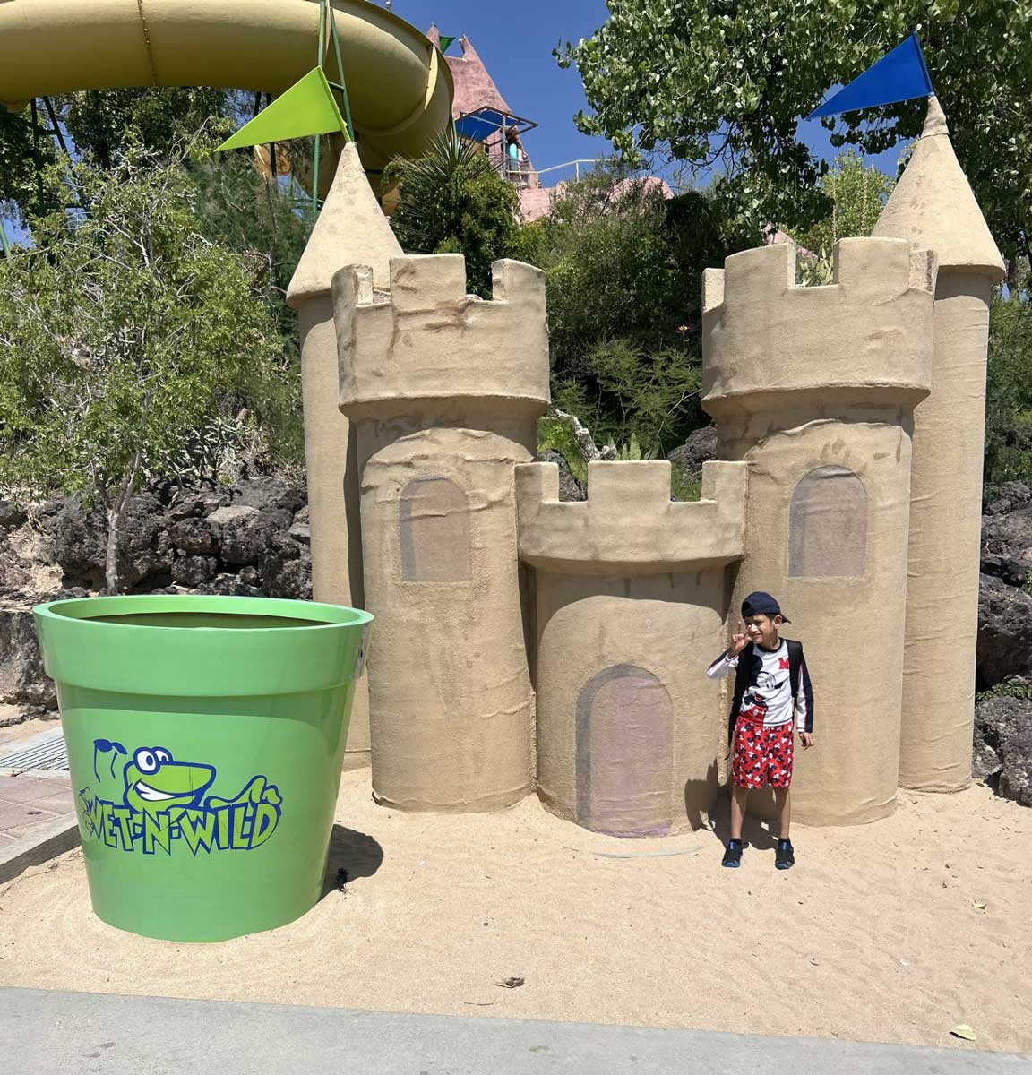 A child next to a large sand castle structure